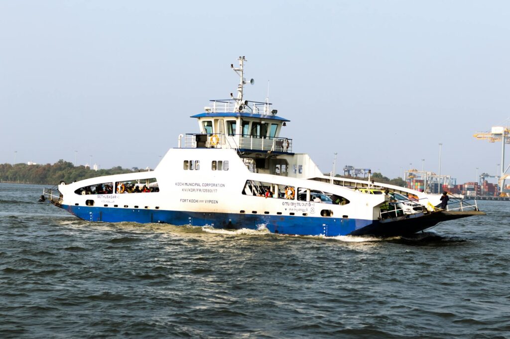 Blue and white ferry navigating through the waters of Kochi, India under a clear sky.